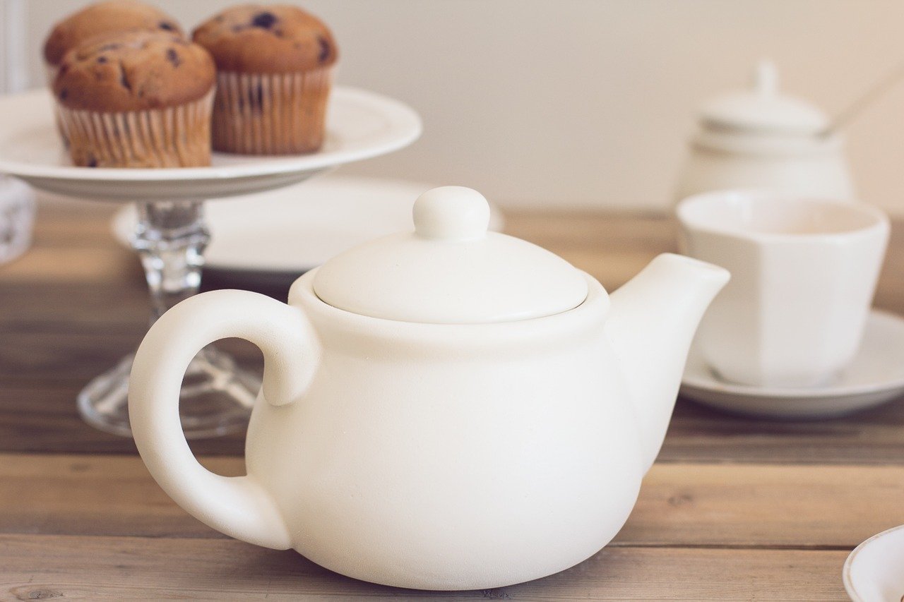 Teapot, teacup and stand of muffins on wooden table