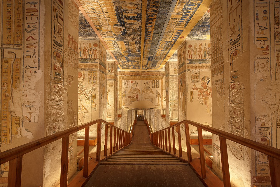 Shot of long walkway descending through a room of hieroglyph-covered walls