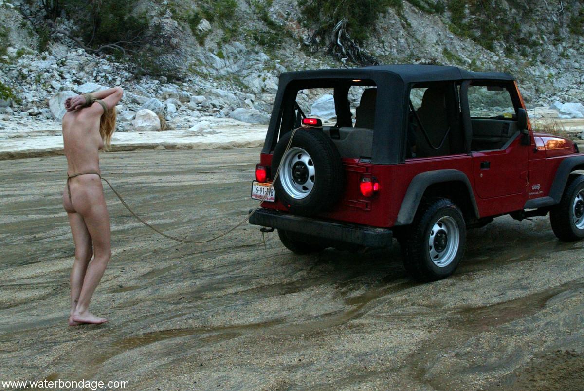 Submissive American walking butt naked tied to a Jeep on the beach(20)