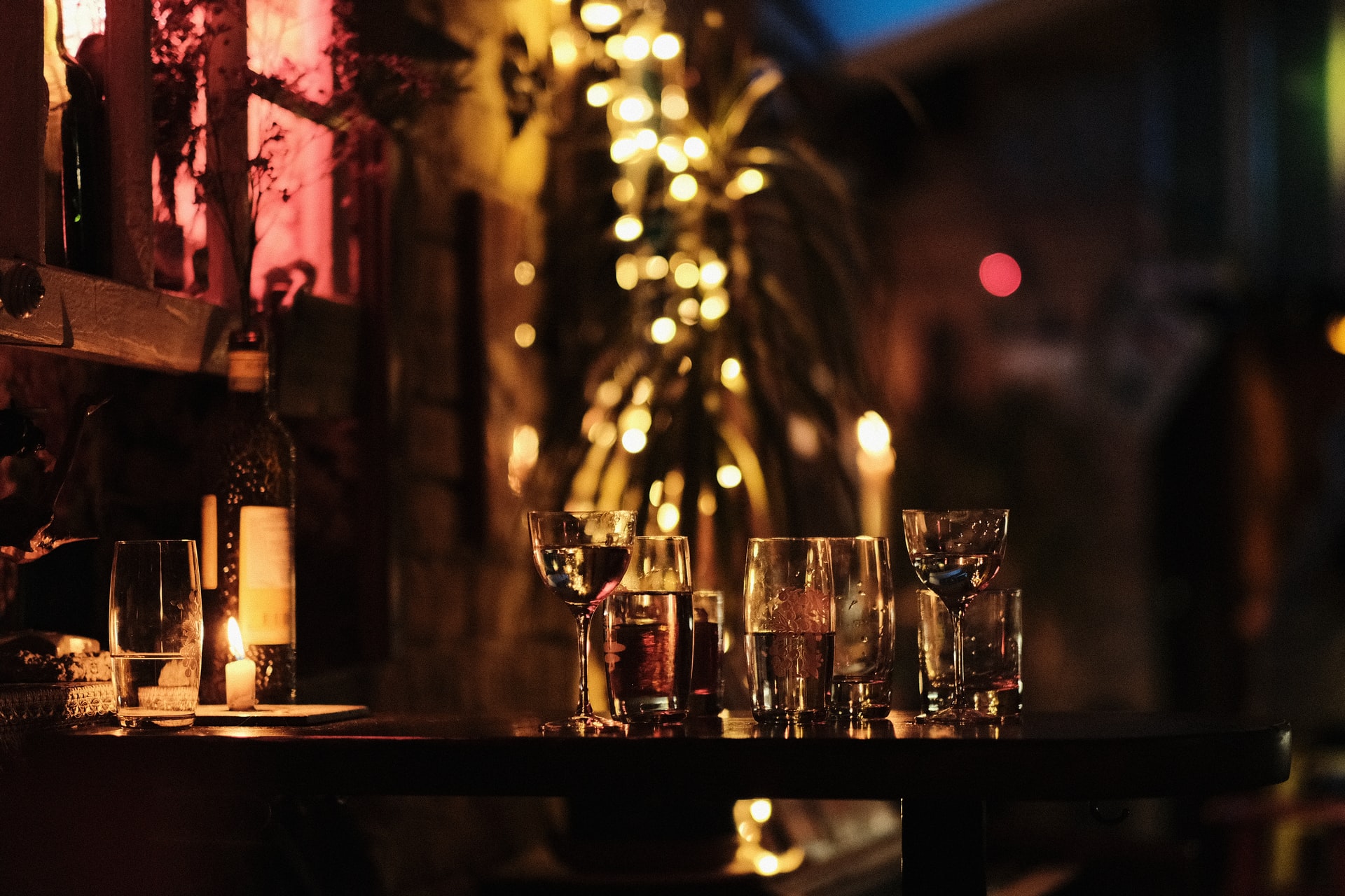 Beer and wine glasses on table outside at night lit by fairy lights in rustic Mediterranean village street
