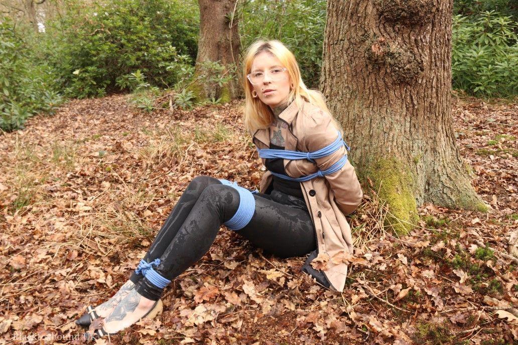 Glasses wearing woman in tied with ropes to a treed in woods with clothes on(16)