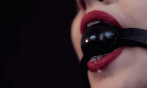 Woman in red lipstick drools around black ball-gag