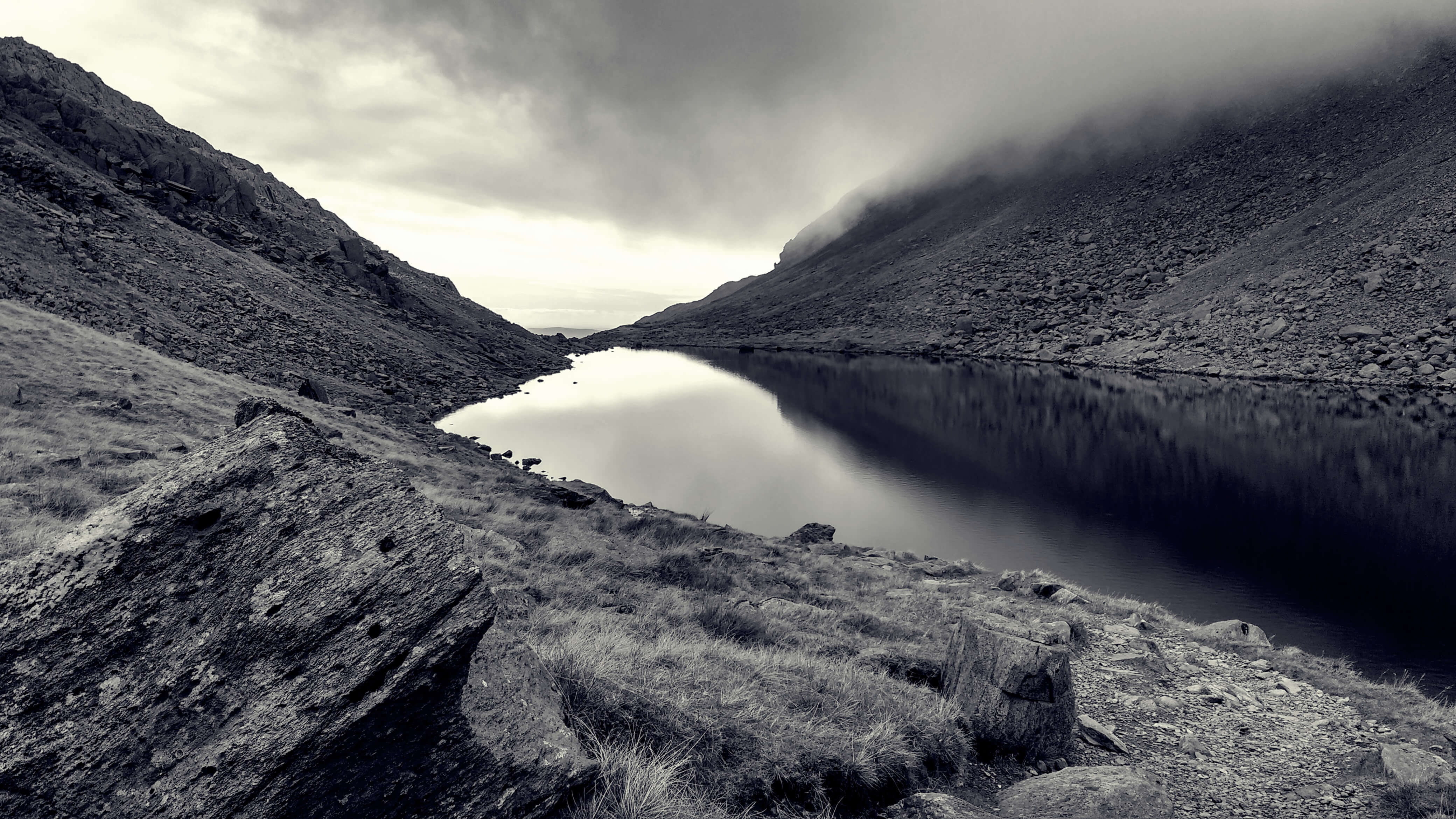 A lake surrounded by rocky hills shrouded in mist