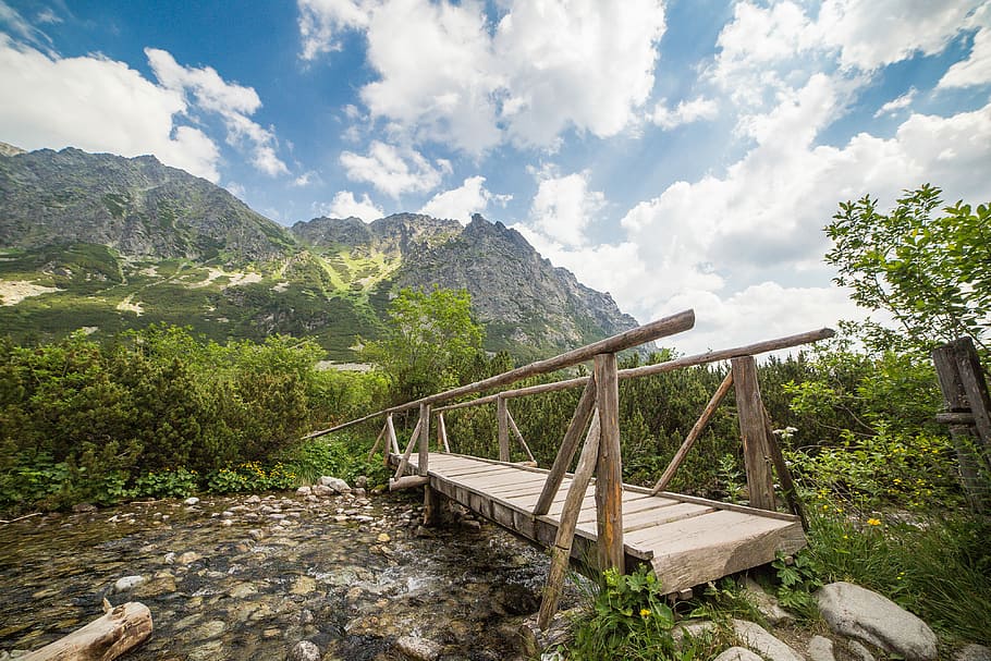 Wooden bridge spans shallow river in mountains