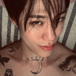 An icon of Jason. His black hair is messy, and he's leaning against a pillow with his shirt off, showing his tattoo's. He is smiling slightly, and looking directly at the camera.