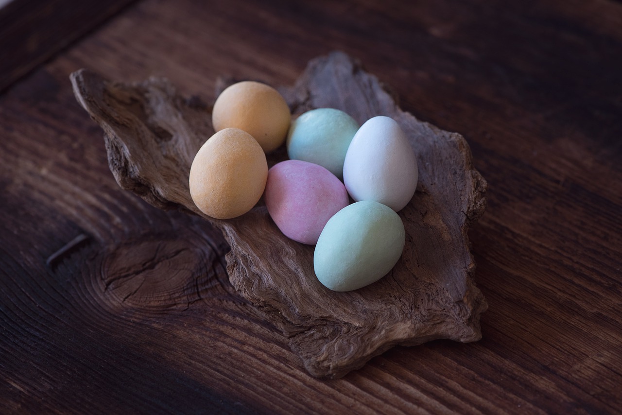 Coloured chocolate eggs on strip of bark on wooden counter