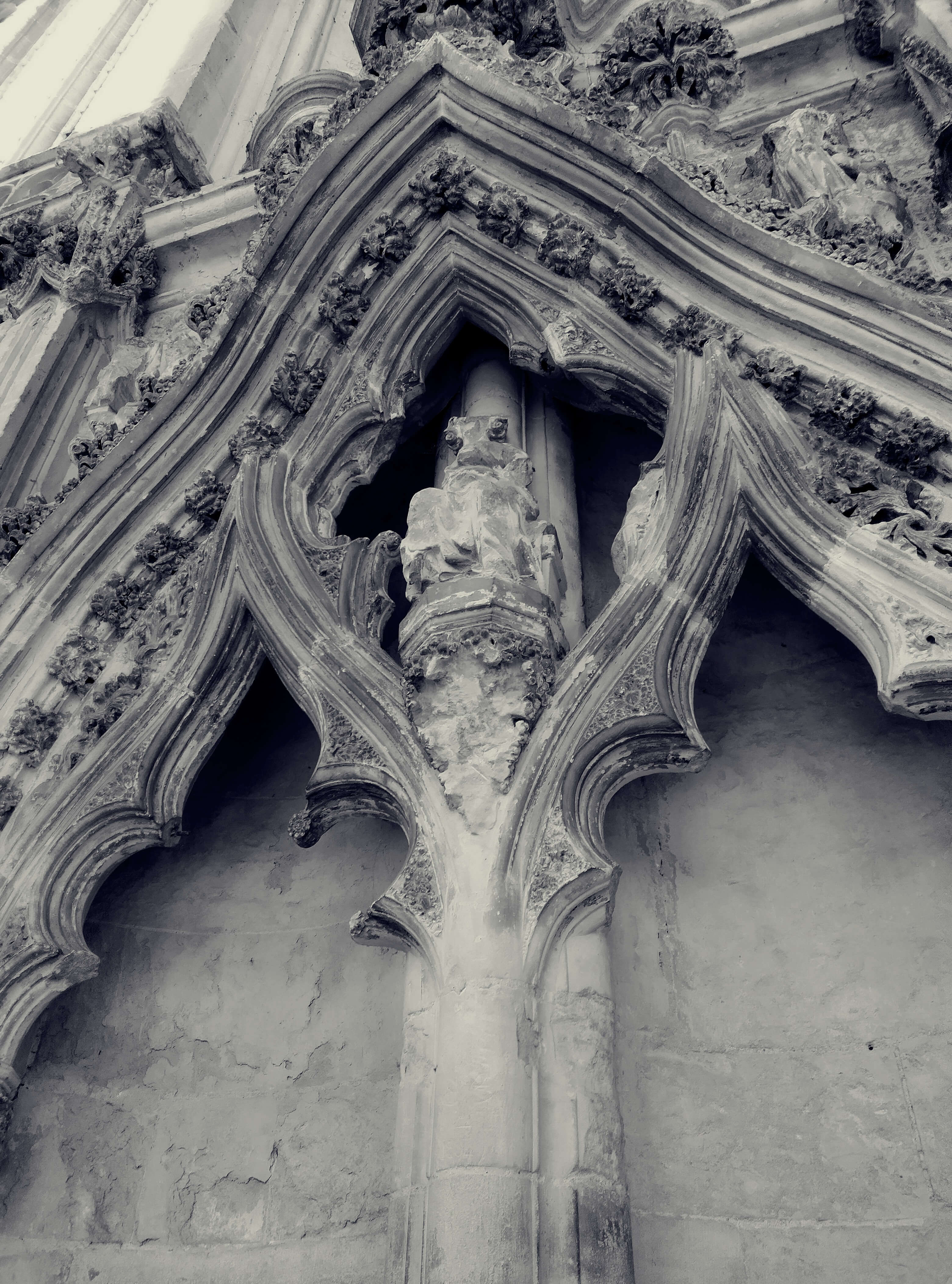 A gothic stone arch with a smashed stone figure at its center