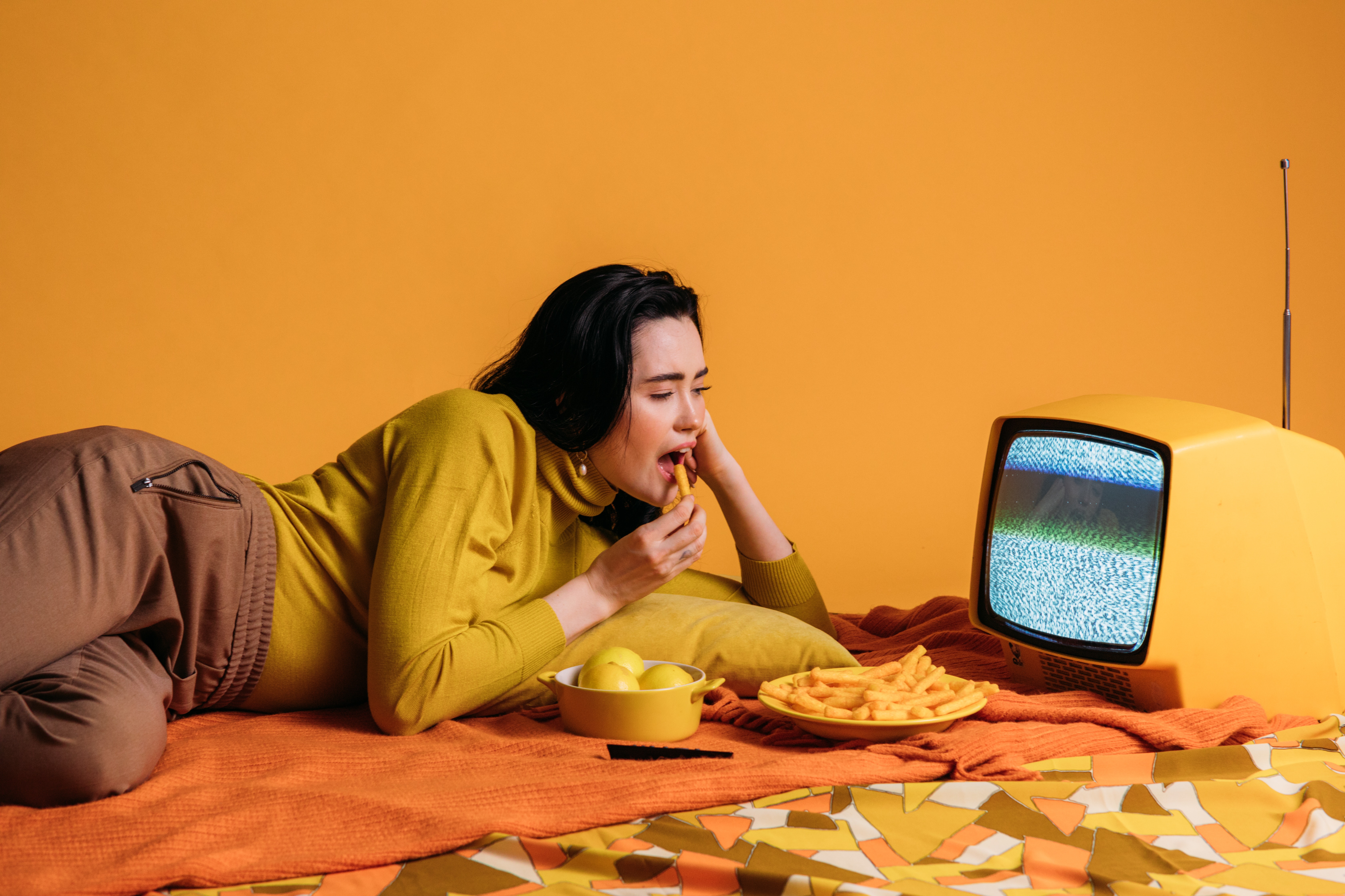 femme mangeant des frites en regardant un écran