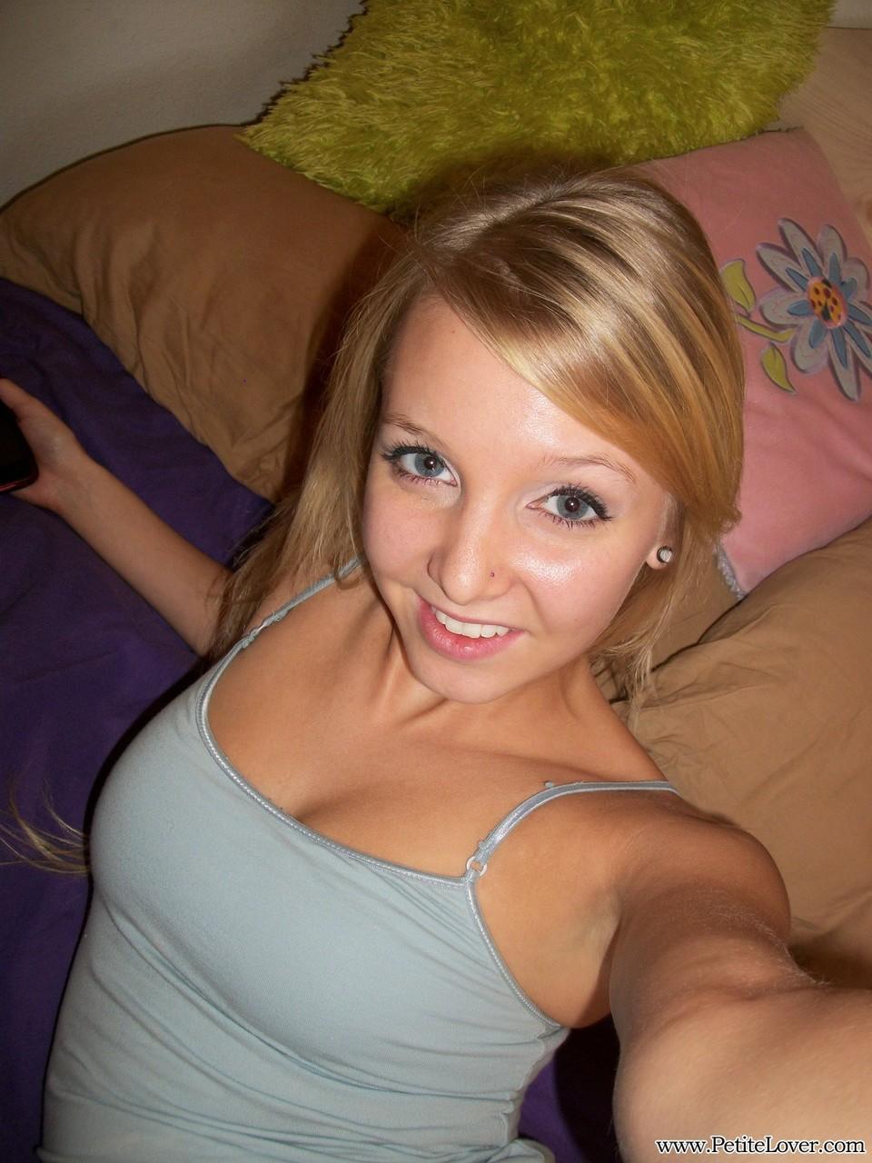 Cute teen girl with blonde hair displays her hairless pussy on her bed(1)