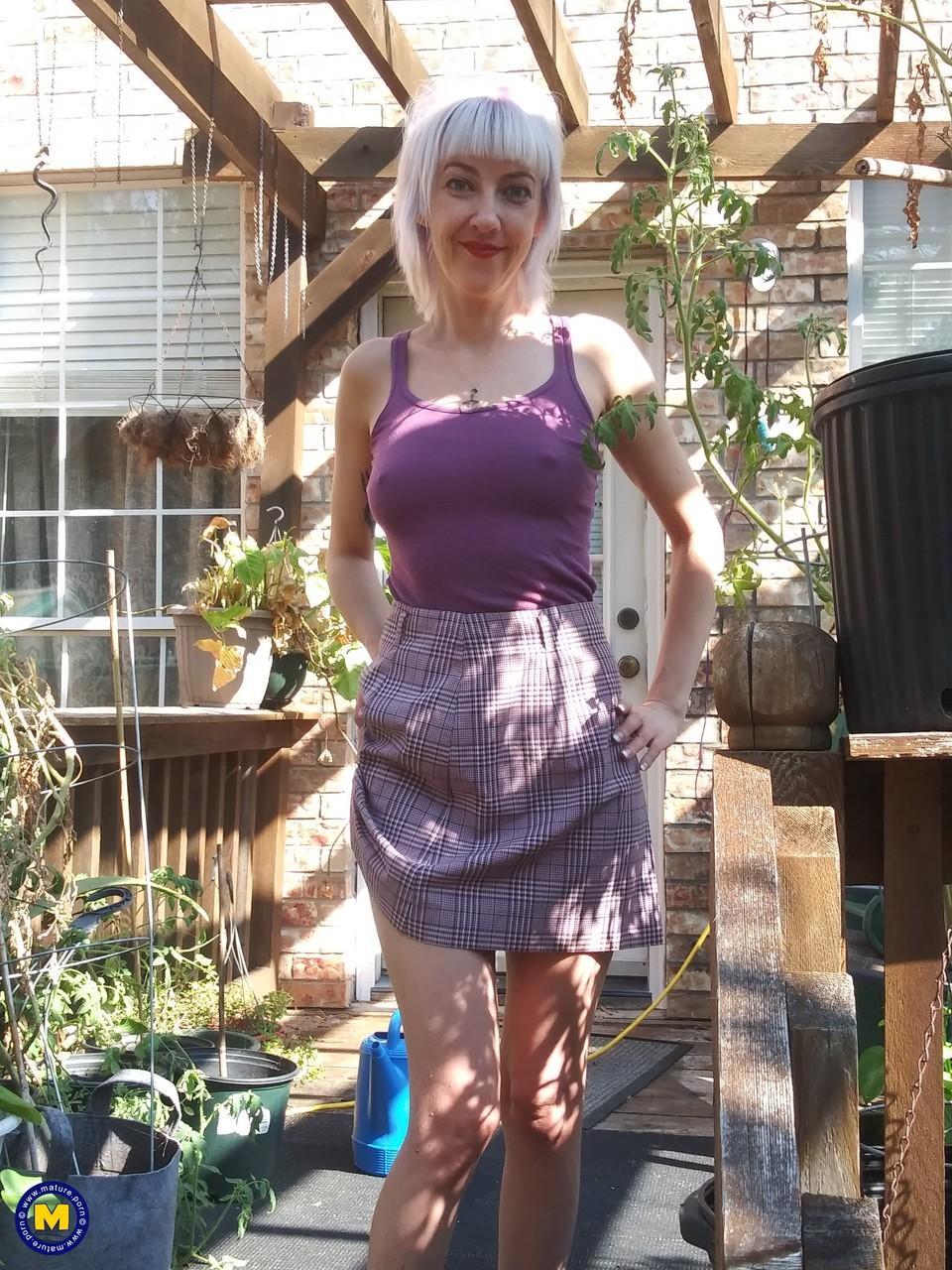 Skinny blonde in a skirt Sylvie J flashing her pussy in an indoor garden(6)