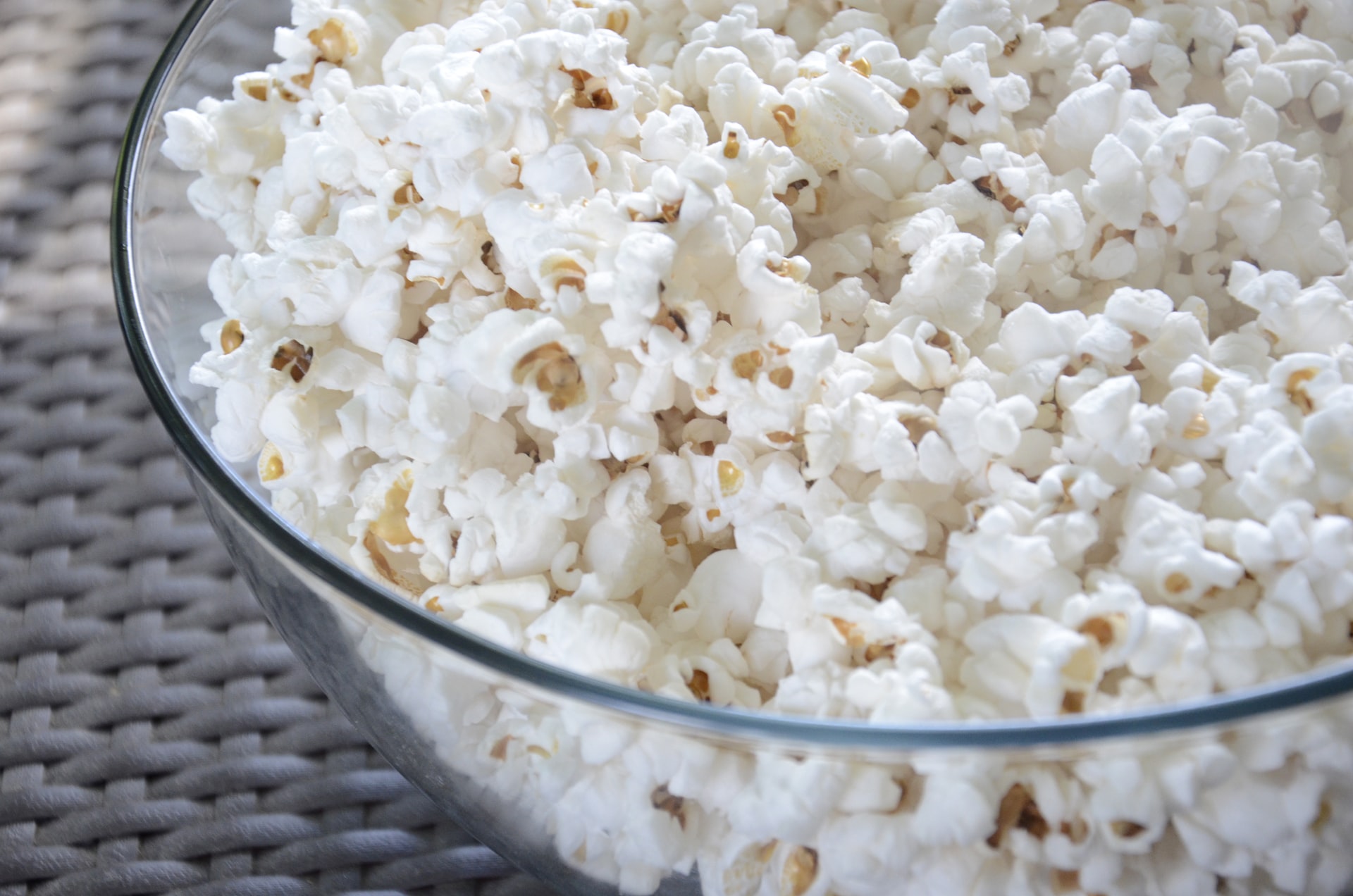 Close-up shot of popcorn in glass bowl on wicker tabletop