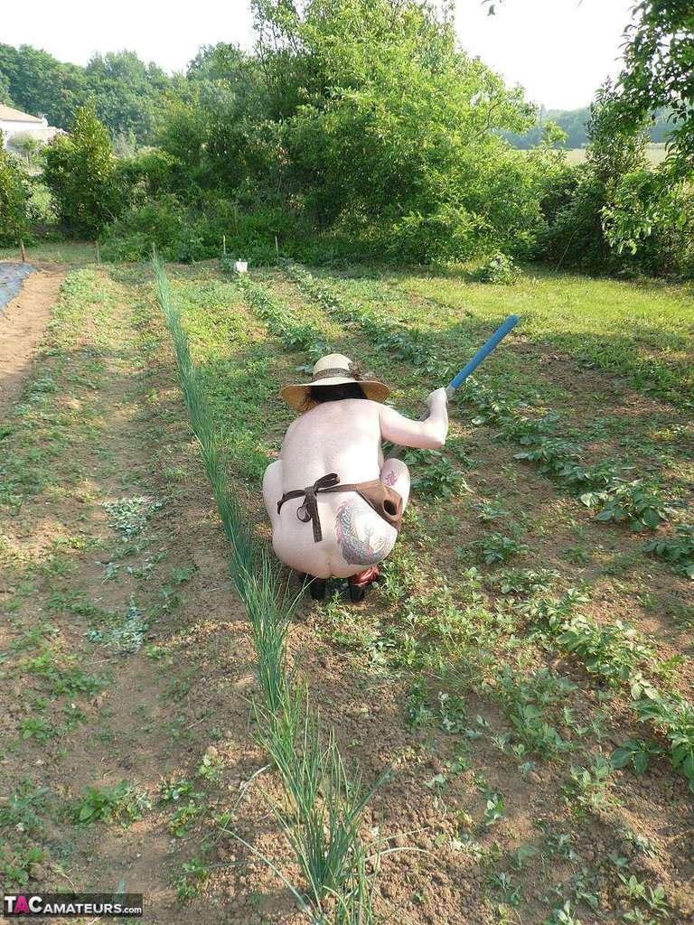 Mature lady Mary Bitch tends to her garden while naked in sunhat and apron(12)