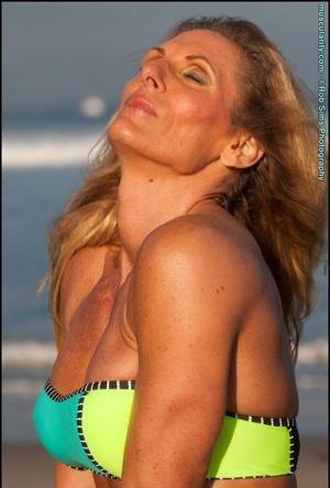 Female bodybuilder Kimberly Dickson poses in a bikini while at the beach