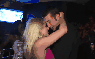 Blonde woman kisses man in black shirt in club