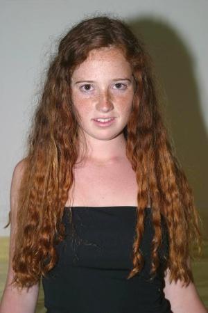 Young looking girl with curly red hair gets totally naked upon her bed