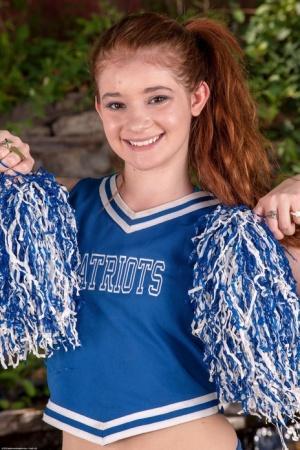 Young looking redheaded cheerleader Ava Sparxxx gets totally naked in a garden