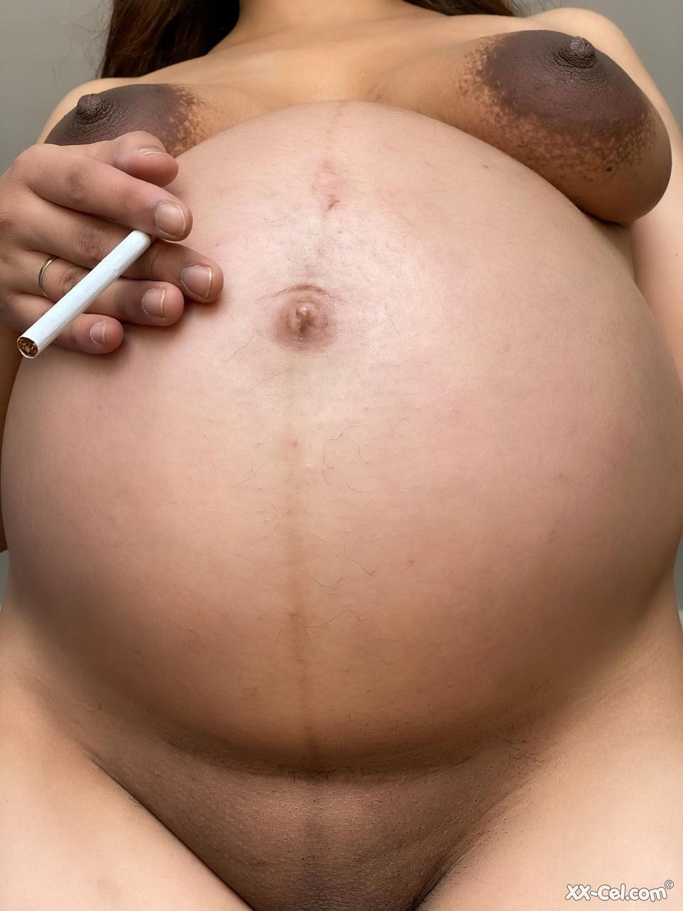 Pregnant smoker Leila teasing nude with her bulging tummy & her dark nipples(19)