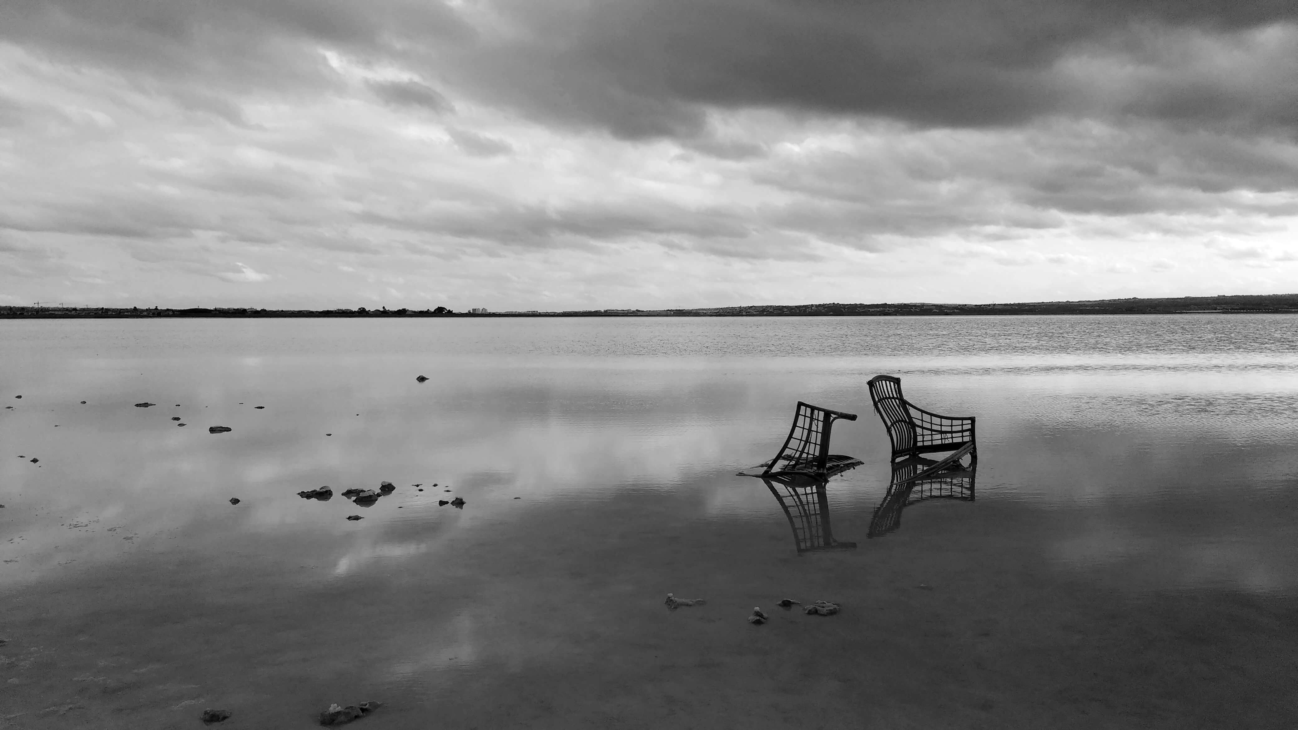 Two abandoned deck chairs sitting in a lake