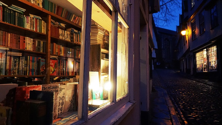 View through bookshop window from cobbled street in evening