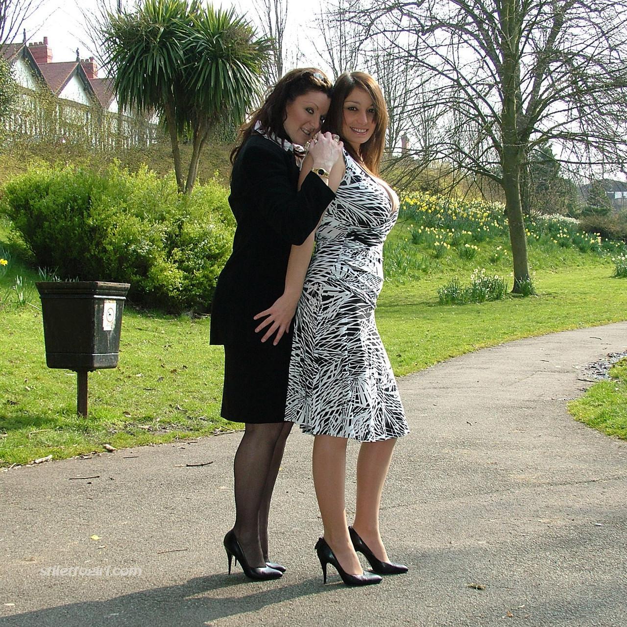 Clothed ladies hold hands while showing their spiked heels on a walking path(14)