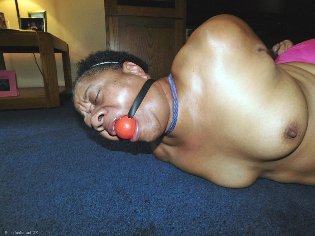 Overweight black woman Trixie struggles against a ball gag while hogtied(1)