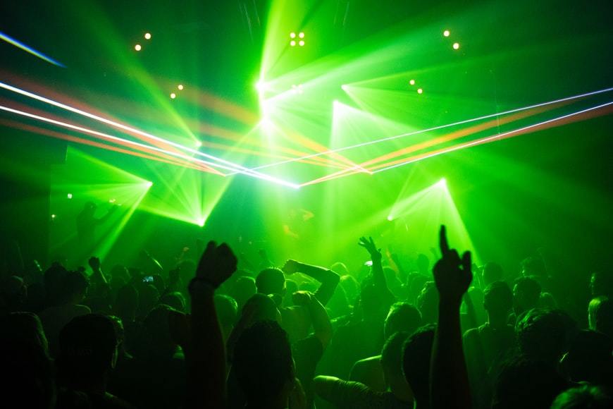 Neon green lighting illuminates crowd in club