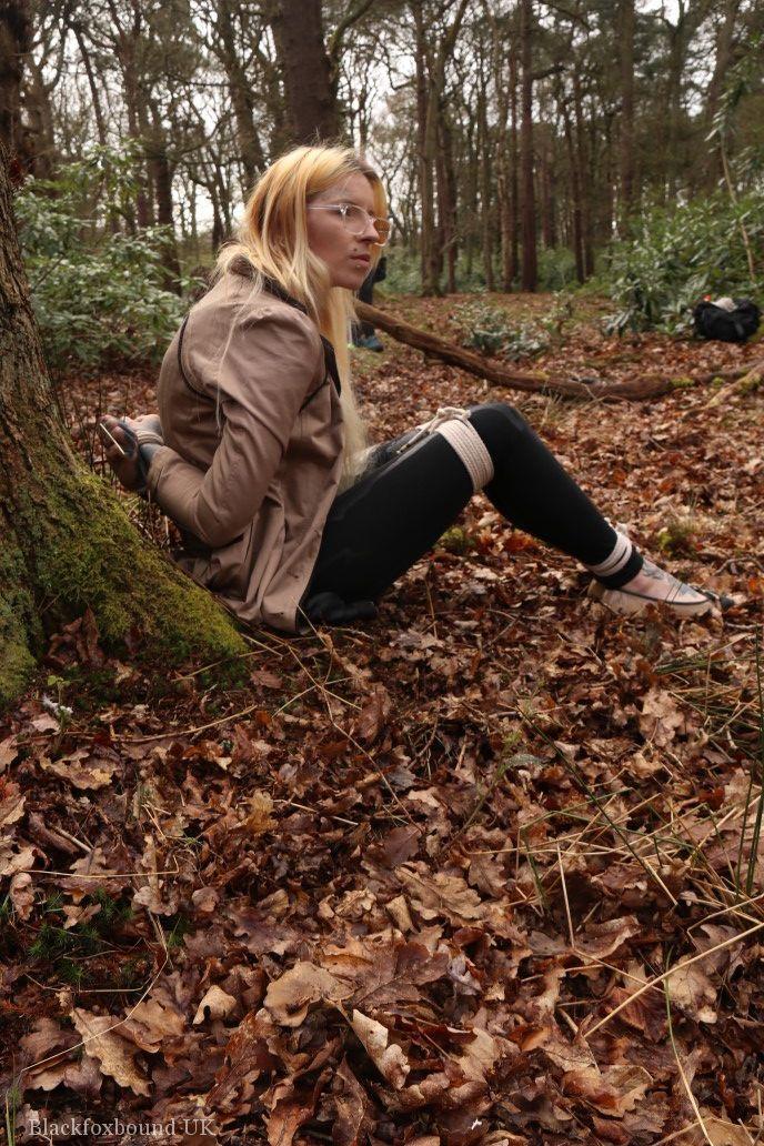 Glasses wearing woman in tied with ropes to a treed in woods with clothes on(8)