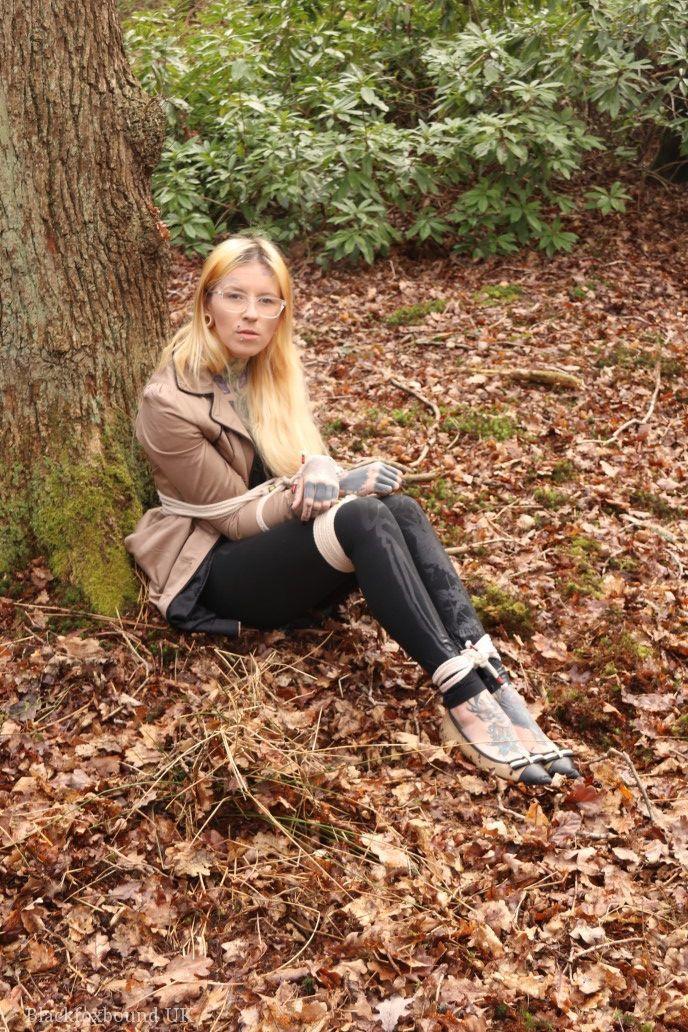 Glasses wearing woman in tied with ropes to a treed in woods with clothes on(4)