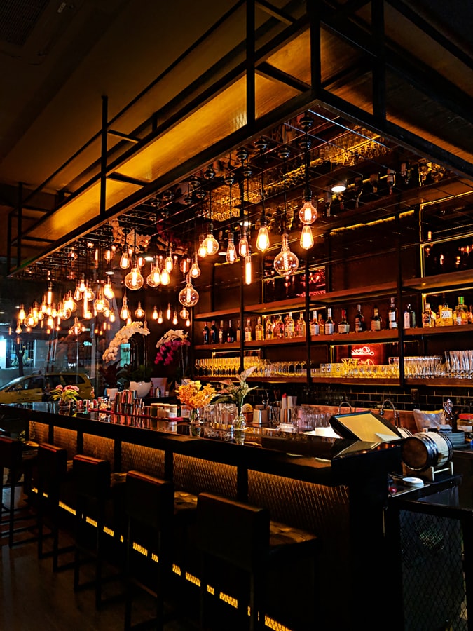 Image of bar with rustic lighting and many bottles lining the shelves