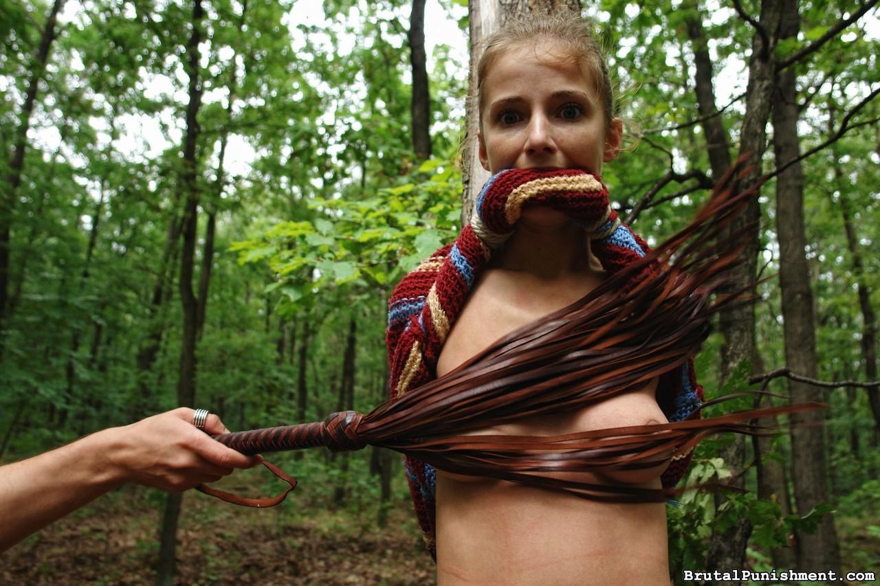 Petite blonde girl is flogged while tied to a tree in the forest(8)