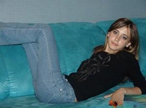 Amateur solo girl in bare feet and jeans starts to remove her sweater