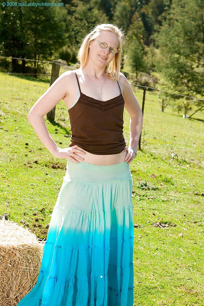 Plain looking blonde girl in glasses strips off blouse and skirt outdoors(1)