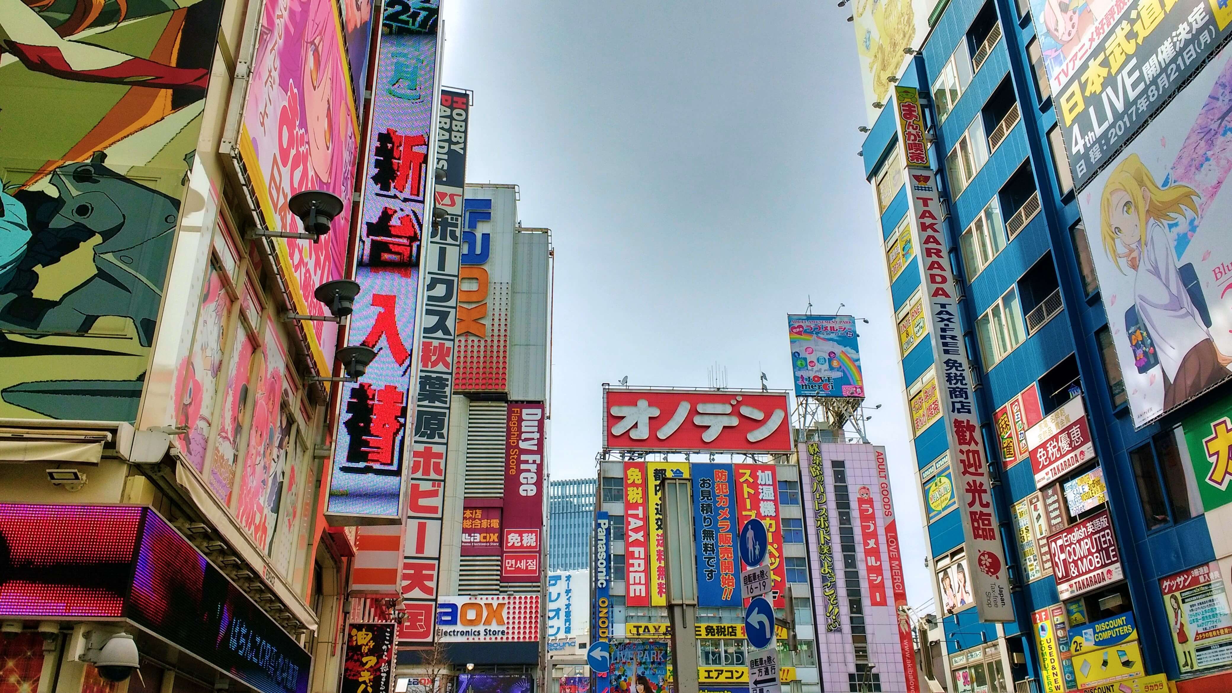Rows of buildings on a city street covered in colourful signs