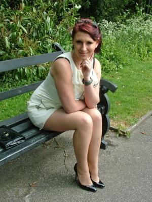 Thick woman in glasses shows off her stiletto heels on a park bench