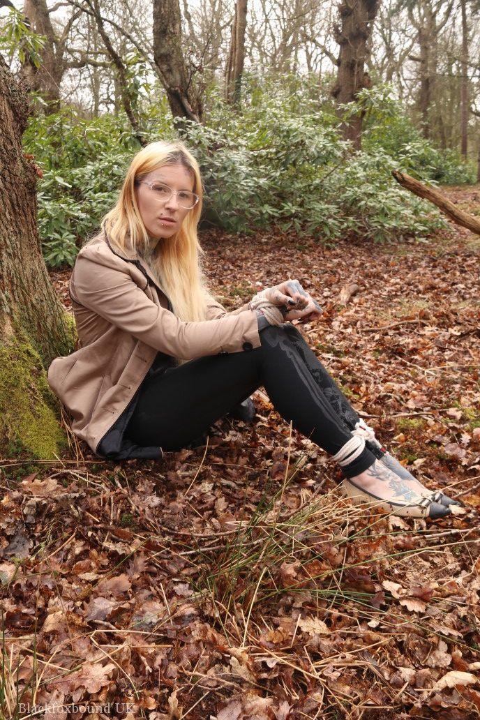 Glasses wearing woman in tied with ropes to a treed in woods with clothes on(2)