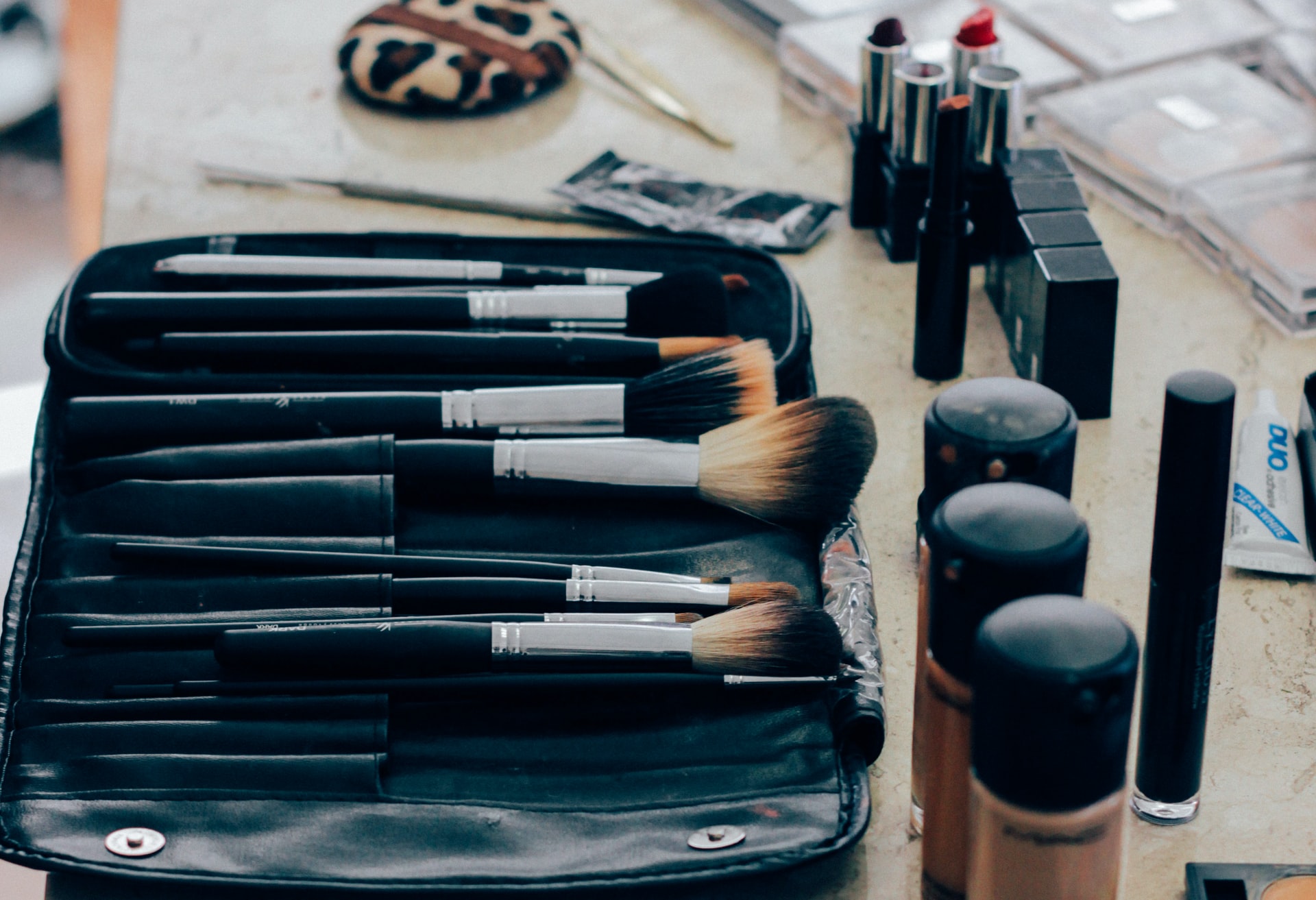 Assortment of makeup brushes and other beauty paraphernalia laid out on marble counter 