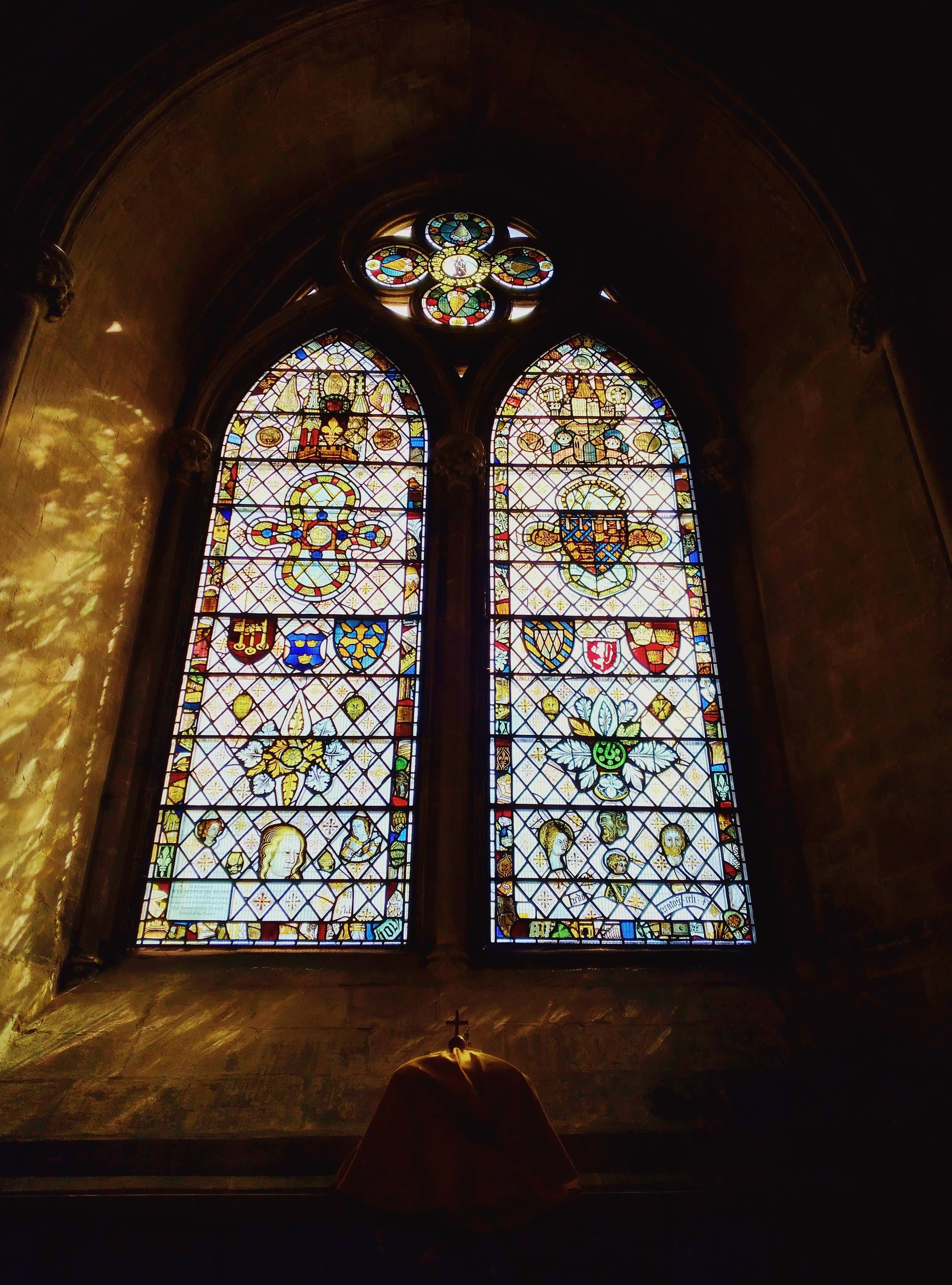 An arched stained glass window above a small cross