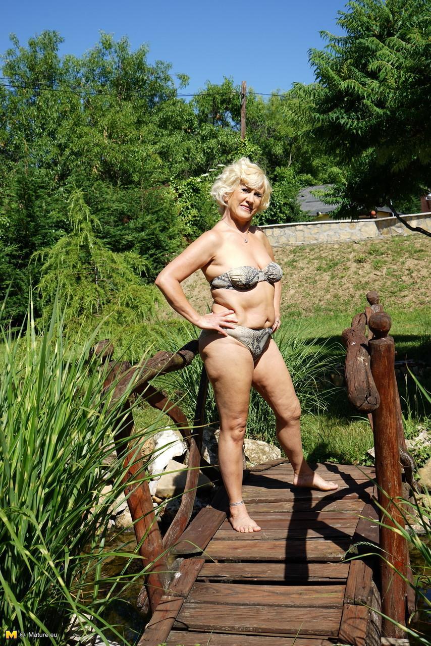 Mature blonde woman takes off her bikini while wandering around her property(4)