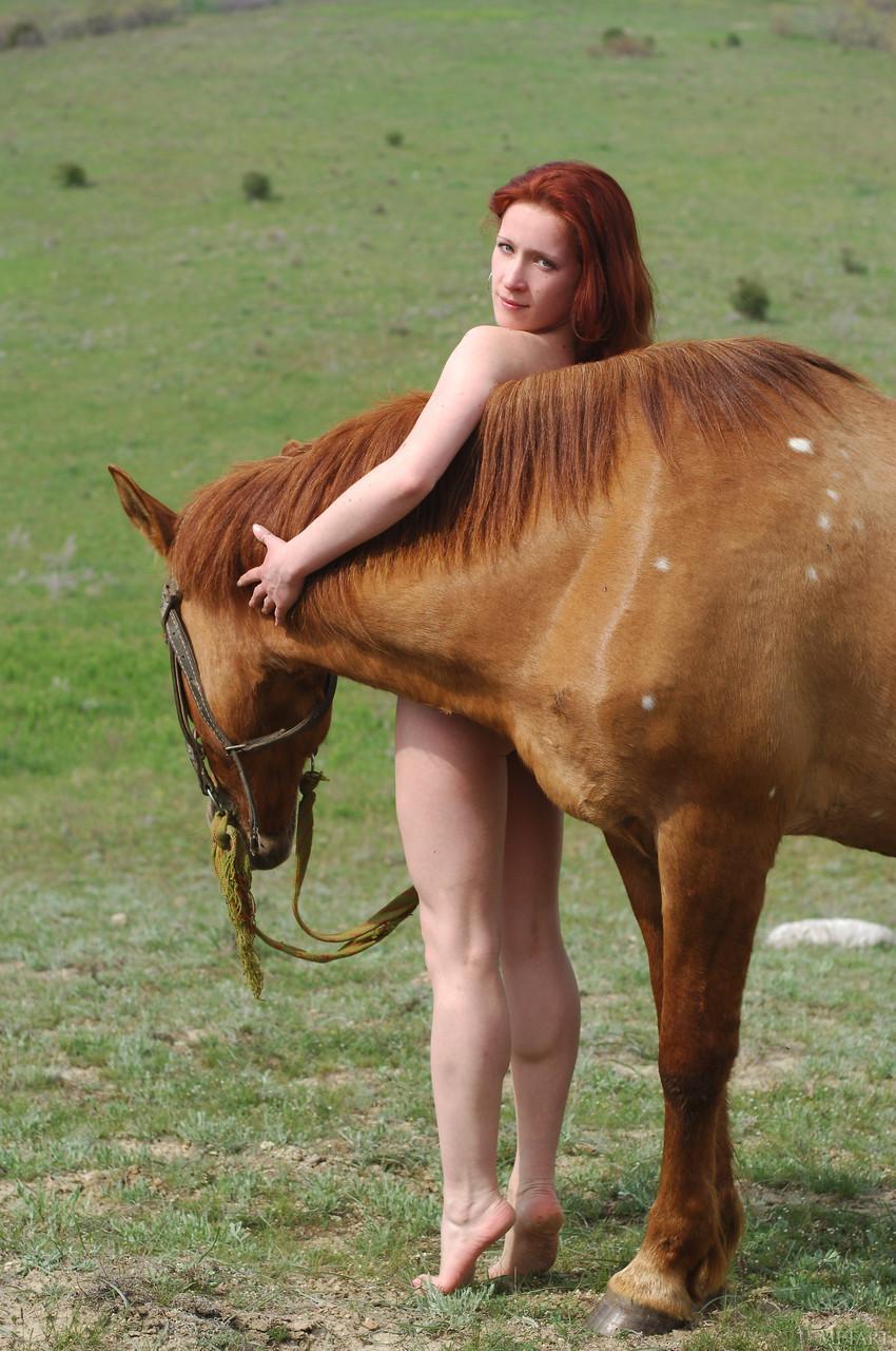 Redheaded teen Klara A poses completely naked on a huge horse outdoors(15)