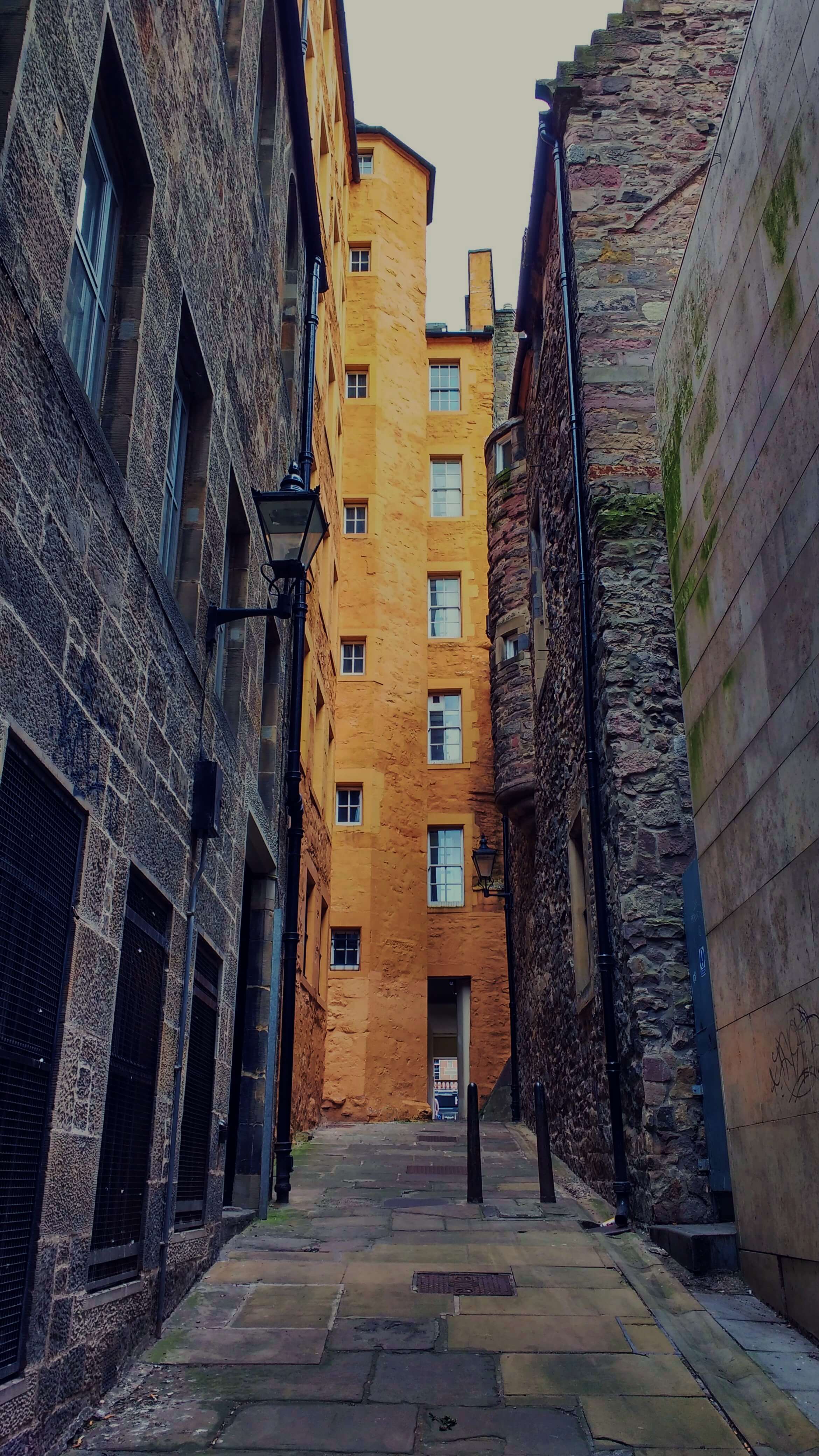 An alleyway leading to a tall orange building