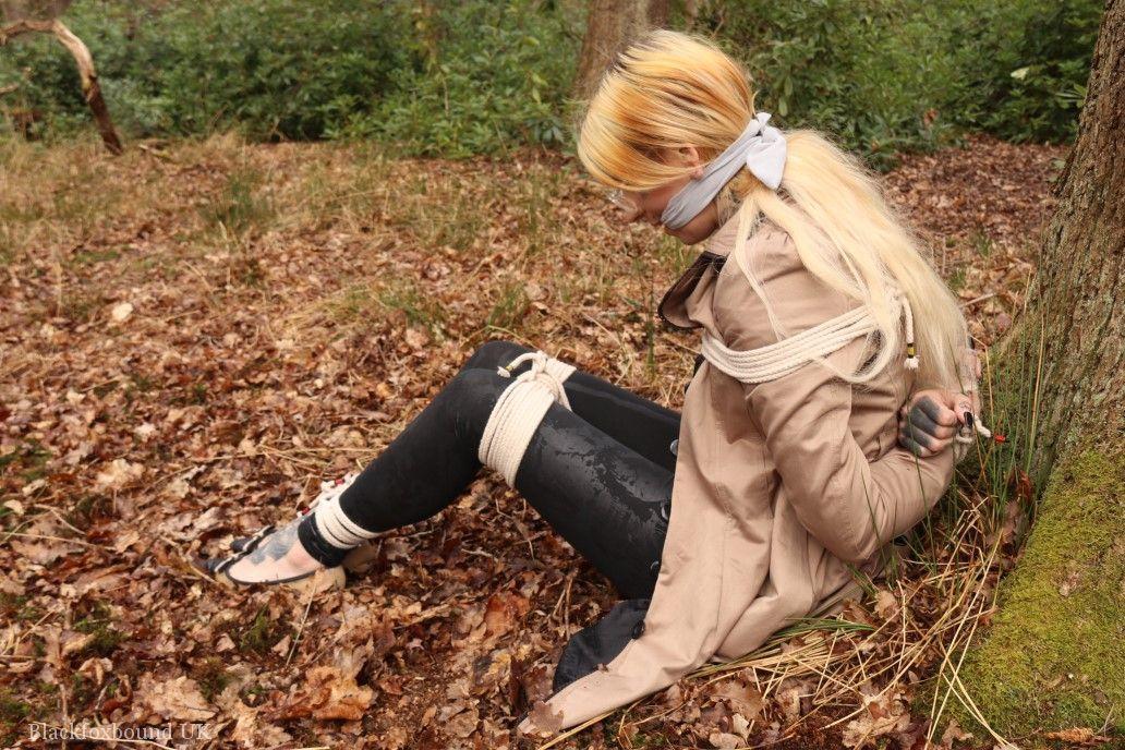 Glasses wearing woman in tied with ropes to a treed in woods with clothes on(13)