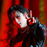 Icon of Haneul. He is standing against a red background and making a 'peace' sign at the camera with a daring expression on his face. He is wearing a leather jacket, and a graphic tee.