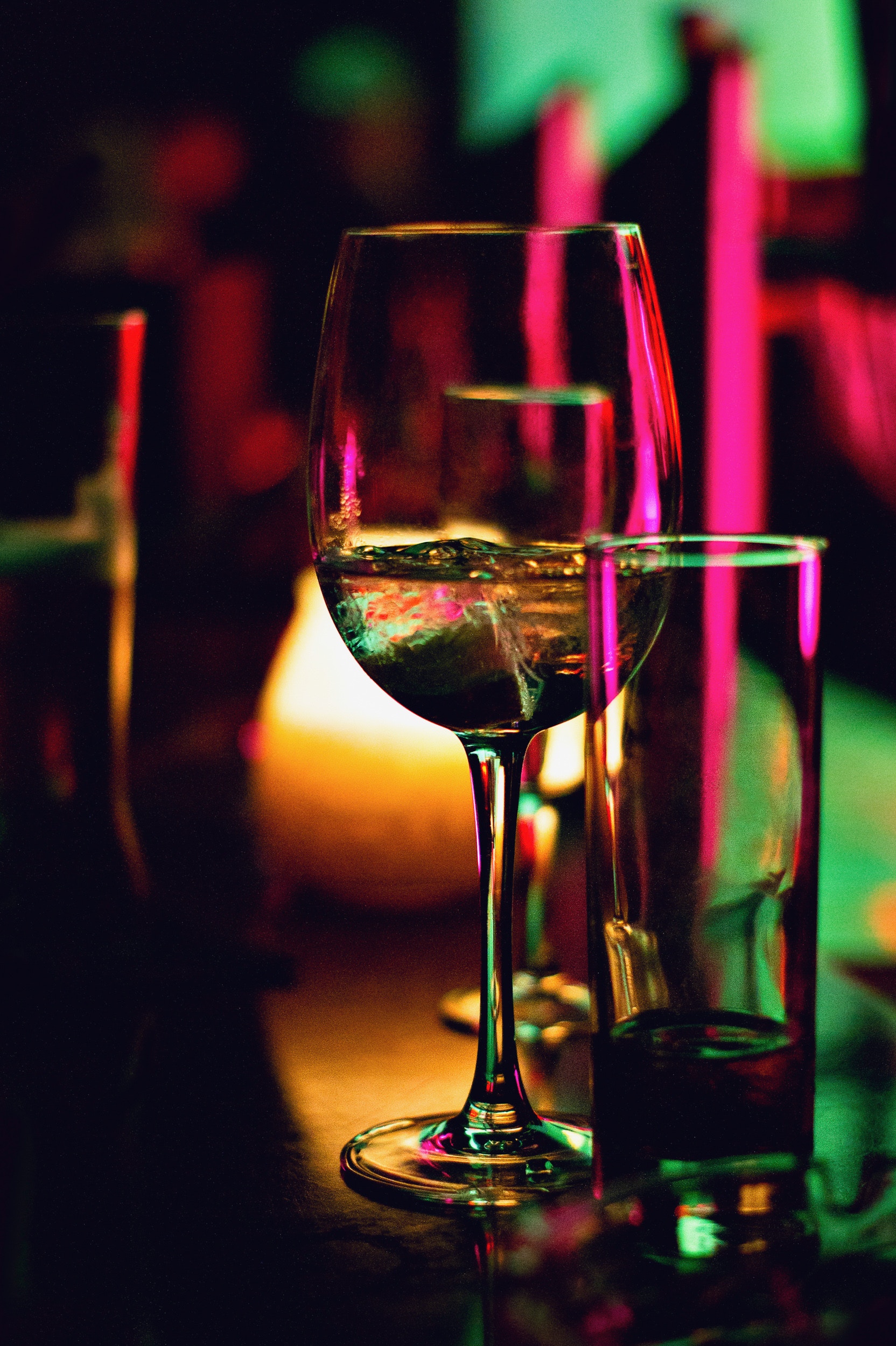 Close-up shot of wine glass on neon-lit bar