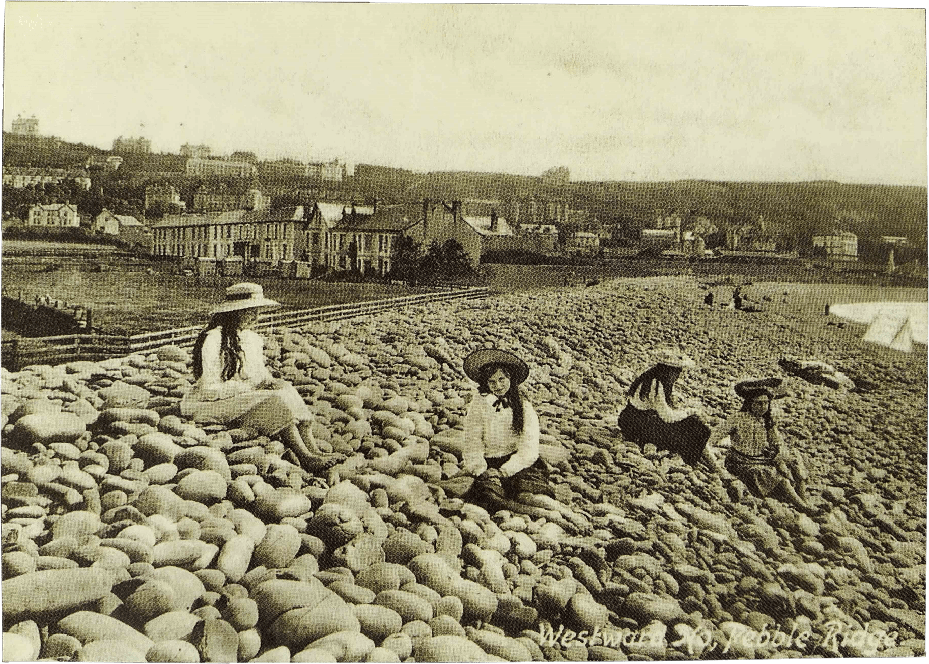 An old photograph of four women and girls sitting on a pebble beach