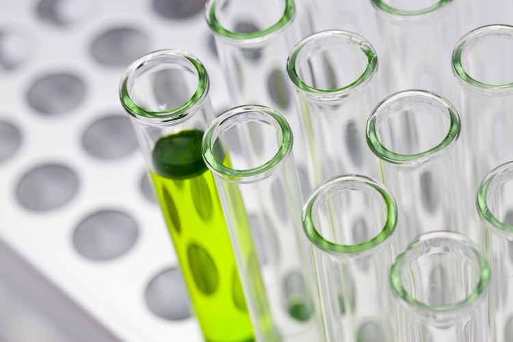 Close-up of test tubes with one full of green liquid