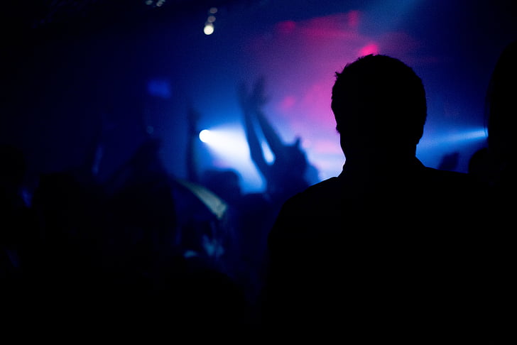 Silhouette of man in dark night club with people dancing in background