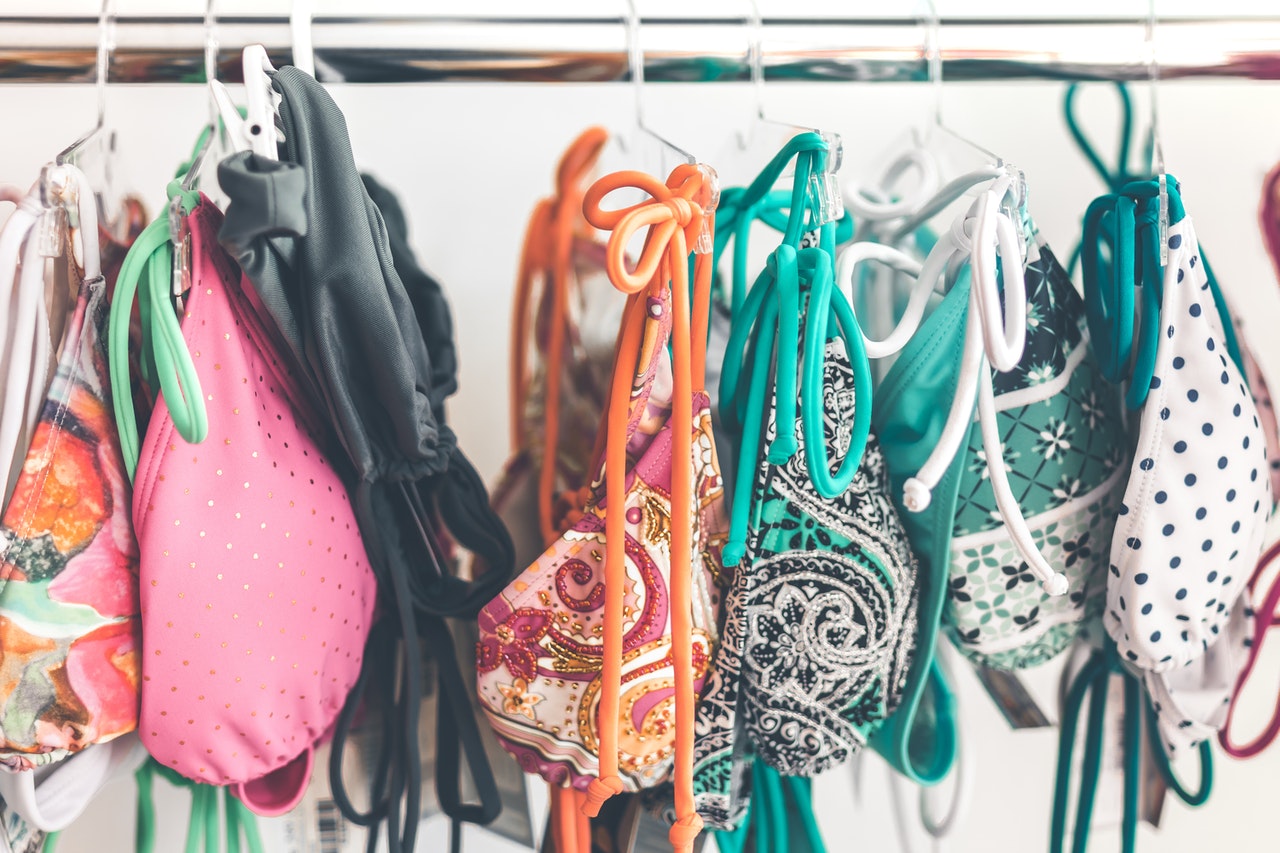 Various multi-coloured bikini sets hang on metal railing